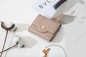 Close-up of light brown leather wallet featuring elegant leaf embroidery and gold hardware