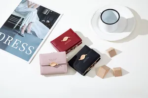 Flat lay of small three-fold leaf buckle wallets in burgundy, pink, and black