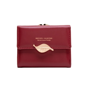 Close-up of red leather tri-fold wallet with elegant gold leaf buckle and stitching