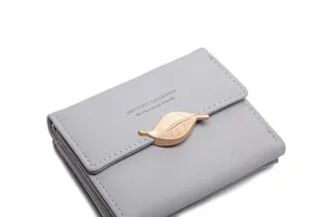 Detail of grey trifold wallet featuring a champagne gold leaf-shaped buckle on PU leather