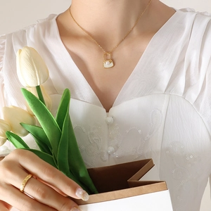 Collier doré élégant avec pendentif sac en perle et bague matelassée sur un mannequin