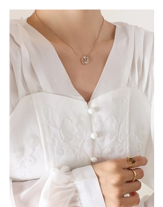 Primo piano della collana camelia in oro rosa e dell'anello con gemma quadrata sulla modella
