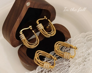 Close-up of gold U-shaped hoop earrings with zircon stones on heart-shaped box