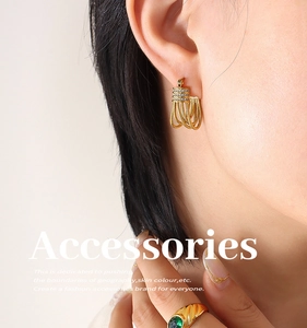 Detail of gold tassel earrings with zircon inlay and green gemstone ring on model