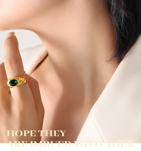 Detail of a vintage-style gold-plated spiral ring featuring an oval green zircon stone