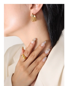 Close-up of elegant gold earrings with pave zircons and a textured wide band ring