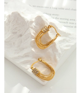 Macro detail of gold U-shaped woven earrings with sparkling cubic zirconia on stone base