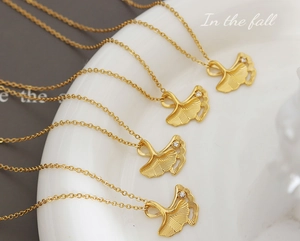 Close-up of golden ginkgo leaf pendant with delicate vein texture and sparkling diamond