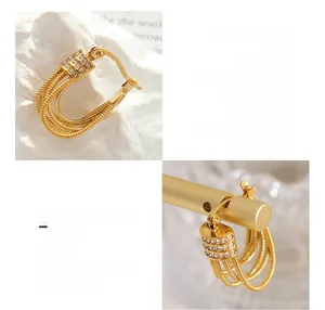 Macro detail of U-shaped gold plated earrings with triple row zircon micro-inlay accents