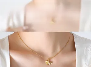 Macro shot of gold ginkgo leaf pendant with zircon inlay on a delicate chain necklace
