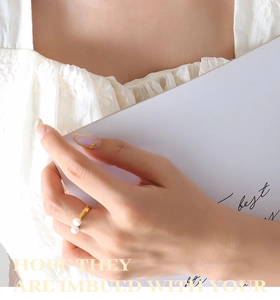 Detailed view of adjustable gold-plated ring with double pearls on a model hand