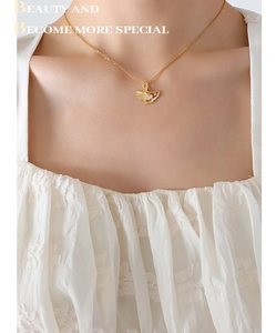 Close-up of a gold ginkgo leaf pendant necklace with a tiny diamond on a model