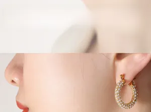 Close-up of model wearing gold U-shaped earrings with pave-set shimmering crystals
