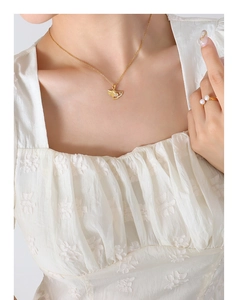 Detail of gold ginkgo leaf necklace with small diamonds and elegant pearl ring
