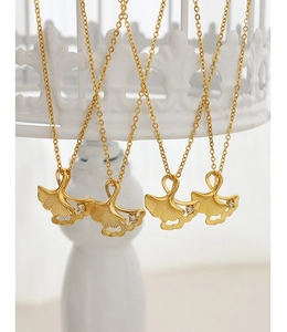 Detailed view of four gold ginkgo leaf pendants with diamond accents on a display