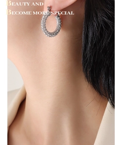 Close-up of a silver U-shaped earring encrusted with sparkling cubic zirconia on a model