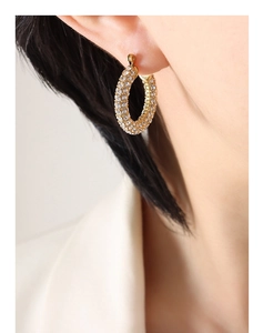 Close-up of elegant gold U-shaped earrings with micro-pave white crystals on a model