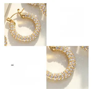 Macro detail of U-shaped surgical titanium earrings with 18K gold and pave zircon stones