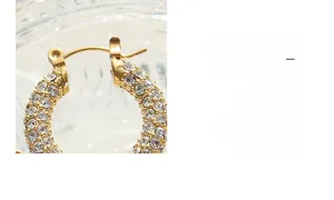 Macro shot of U-shaped gold-plated hoop earrings featuring micro-pave sparkling crystals