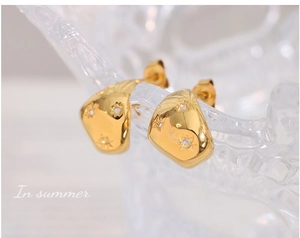 Vue détaillée des boucles d'oreilles géométriques dorées avec étoiles et zircons brillants