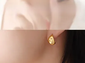 Détail de la boucle d'oreille dorée avec relief d'étoile portée sur le lobe
