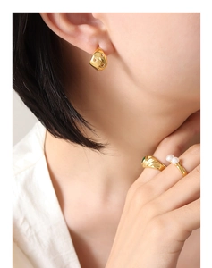 Détails de boucles d'oreilles étoile dorée et bague gemme verte sur mannequin
