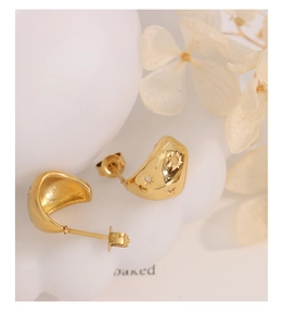 Gros plan détaillé des boucles d'oreilles dorées avec étoiles sur un support ondulé blanc