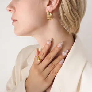 Luxurious gold tiered tassel earrings and large crystal ring set on a model in beige