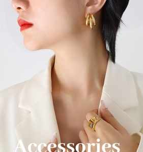 Detail of gold triple-layered C-shaped hoop earrings and geometric ring on a model