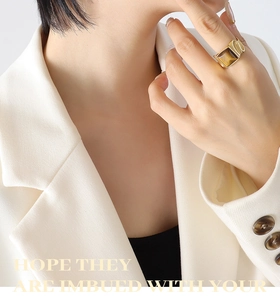 Detailed view of wide gold tiger eye ring worn by model against a white suit background