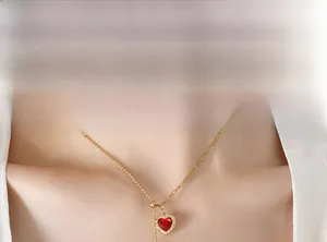 Close-up of golden dual-style chain with a red heart zircon pendant on a model