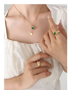 Detail of vintage heart necklace and textured gold rings with green zircon stones
