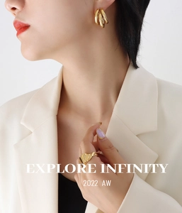 Detail view of gold triple C-shaped hollow hoop earrings and a textured wave ring