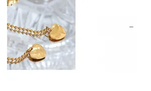 Detailed close-up of gold heart pendant with bead chain and elegant glass refraction