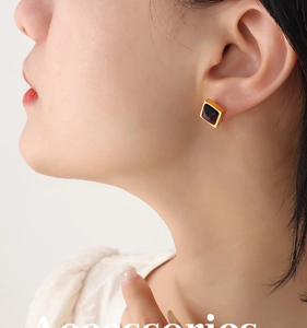 Vue détaillée de boucles d'oreilles carrées dorées avec pierres sombres sur mannequin