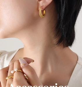 Détail de boucles d'oreilles C dorées 18 carats avec texture vintage et bagues perles