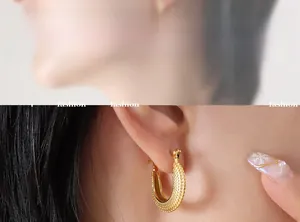 Détail macro d'une boucle d'oreille en C en acier titane doré avec texture perlée