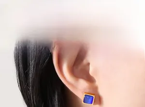 Détail de boucles d'oreilles carrées plaquées or avec pierre œil de chat bleue