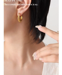 Détail de boucle d'oreille créole en C plaquée or 18K avec fini martelé sur modèle