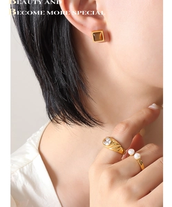 Gros plan de boucles d'oreilles dorées avec oeil de tigre et bagues assorties sur un mannequin