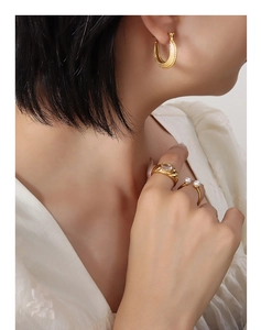 Gros plan de boucles d'oreilles C dorées à pois et bagues en zircon sur modèle