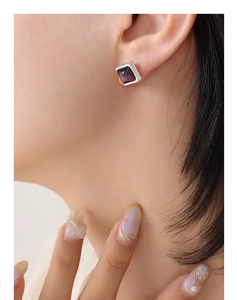 Gros plan détaillé d'une boucle d'oreille carrée en argent avec une pierre œil de tigre violette