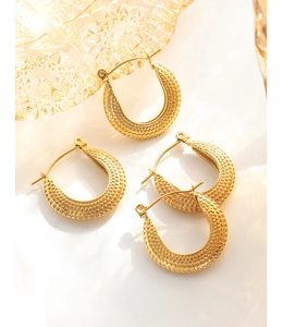 Détail macro de boucles d'oreilles en C plaquées or 18K avec texture à pois