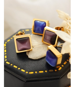 Détail macro de boucles d'oreilles carrées œil-de-chat avec bords dorés sur fond noir