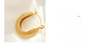 Détail de boucles d'oreilles en C plaquées or 18K avec une surface à pois texturée