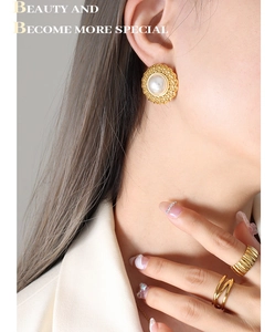 Detail of vintage gold pearl earrings and stacked rings on model in French style