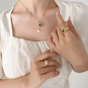 Gold tassel necklace with green heart pendant and matching stone rings worn by model