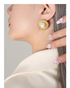 Detail of French vintage gold stud earring with pearl and woven texture on model