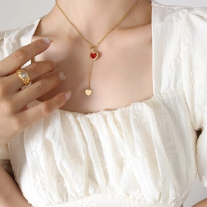 Golden Y-necklace with red heart gemstone and tassel detail on female model