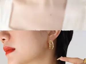 Détail de boucles d'oreilles dorées multicouches en forme de C avec texture torsadée